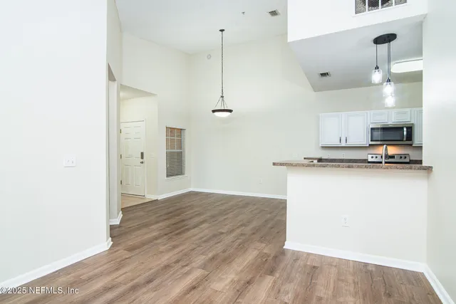a view of kitchen and empty room with wooden floor