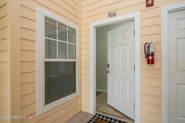 a view of a white house next to a yard with big trees
