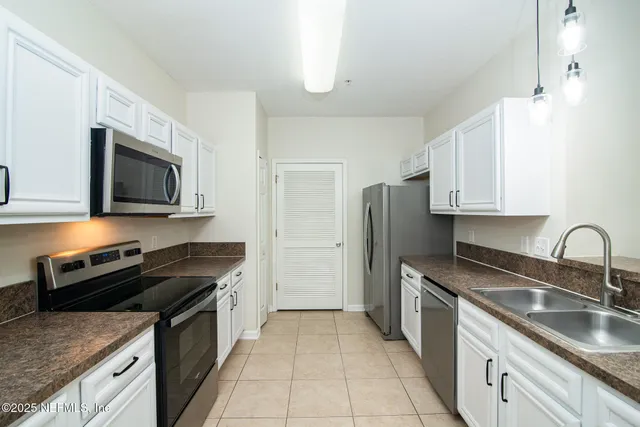 a kitchen with granite countertop a sink dishwasher stove and refrigerator with wooden floor