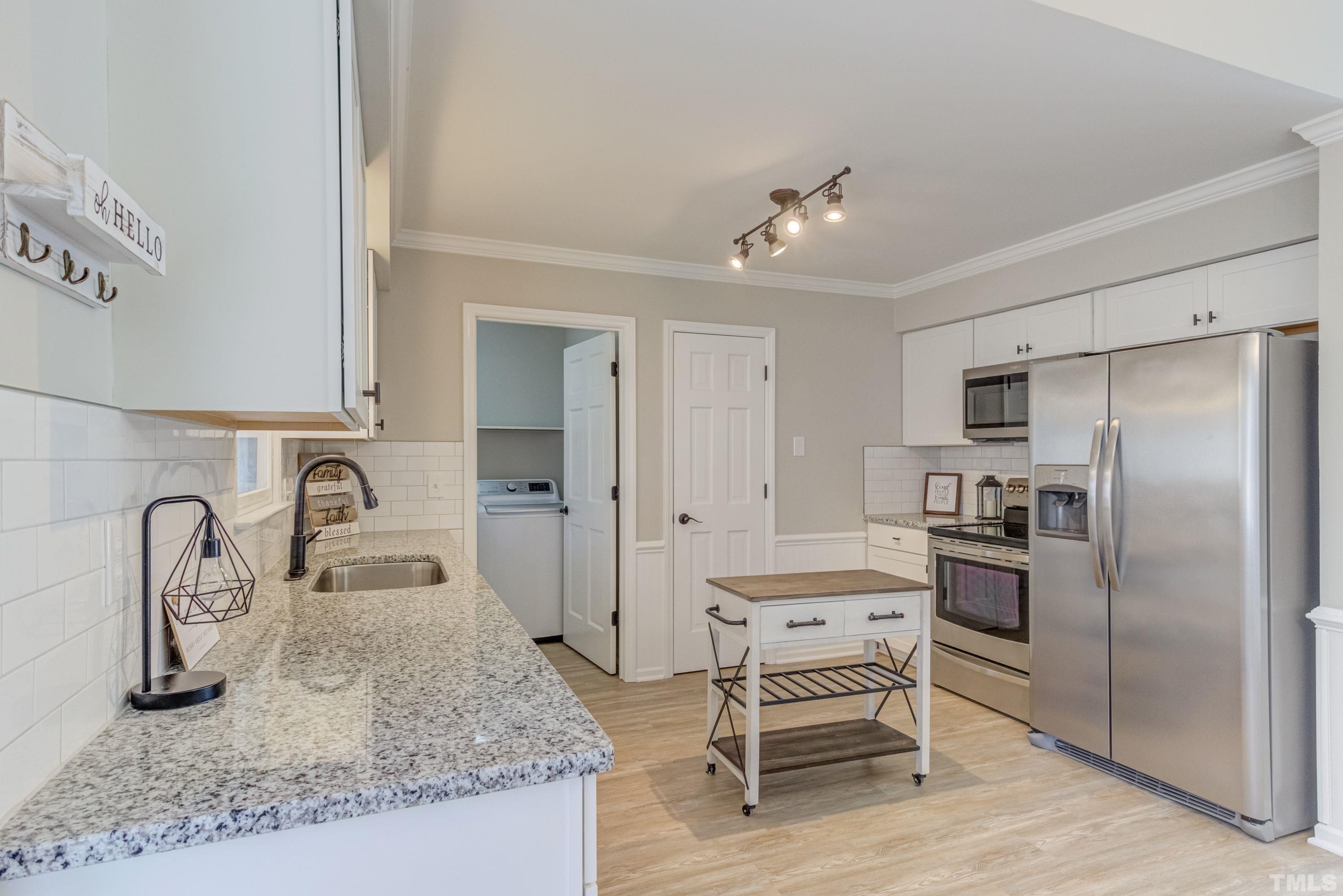 9305 Tallgrass Road Raleigh, NC 27603 - Photo 15 of 49 a kitchen with granite countertop a sink stainless steel appliances and cabinets