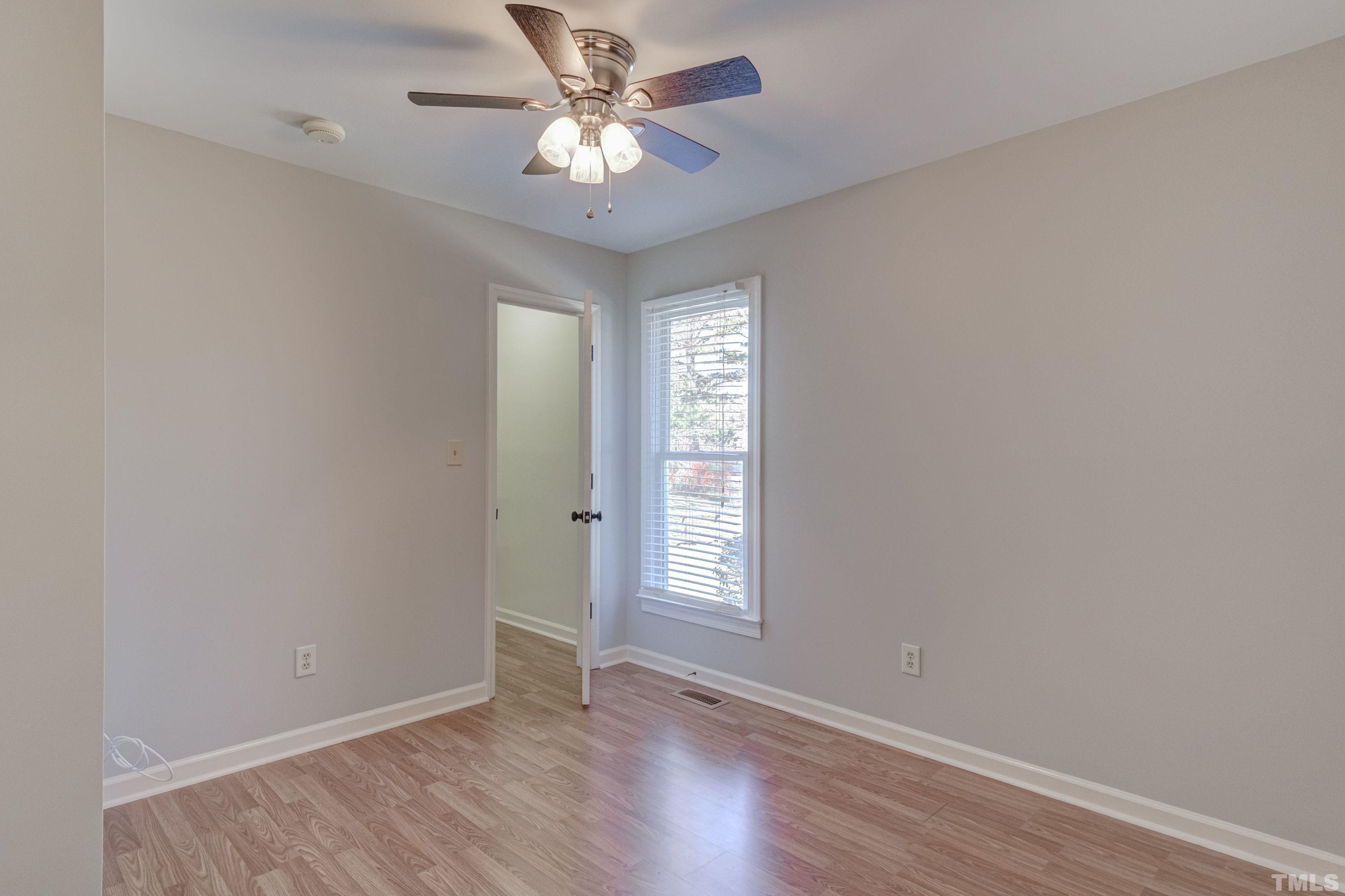 9305 Tallgrass Road Raleigh, NC 27603 - Photo 38 of 49 an empty room with wooden floor chandelier fan and windows