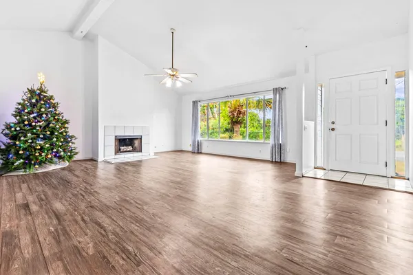 a view of an empty room with window wooden floor and a kitchen
