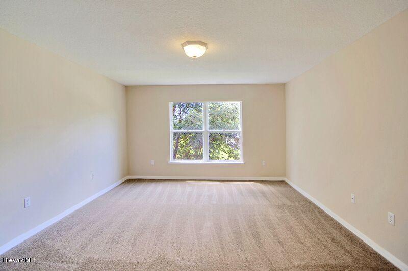 2139 Watkins Road Southeast Palm Bay, FL 32909 - Photo 16 of 32 an empty room with wooden floor and windows