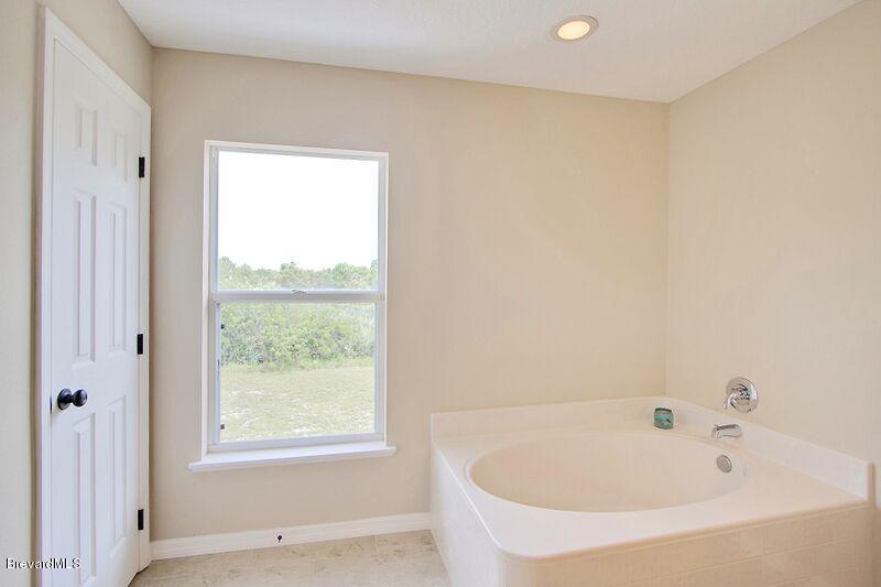 2139 Watkins Road Southeast Palm Bay, FL 32909 - Photo 19 of 32 a white bath tub sitting in a bathroom next to a window