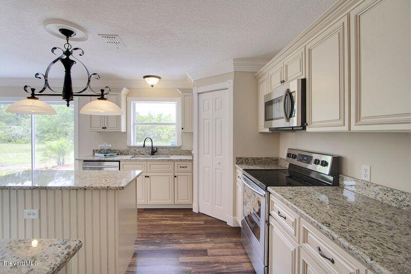 2139 Watkins Road Southeast Palm Bay, FL 32909 - Photo 7 of 32 a kitchen with stainless steel appliances granite countertop a sink stove and cabinets