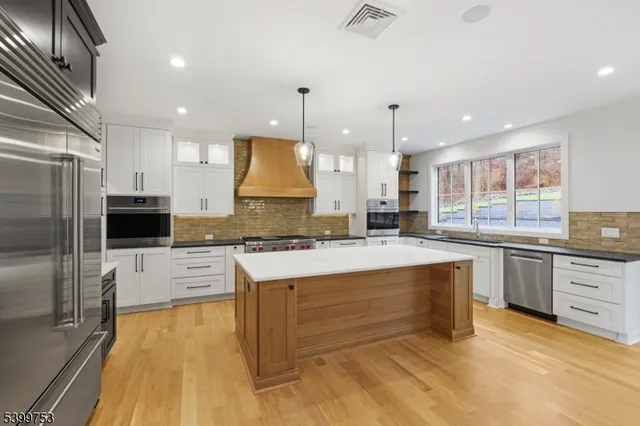 a large kitchen with kitchen island a large counter top space a sink stainless steel appliances and cabinets