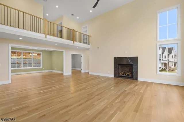 an empty room with wooden floor fireplace and windows