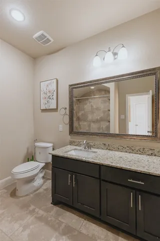 a bathroom with a granite countertop sink mirror vanity and toilet
