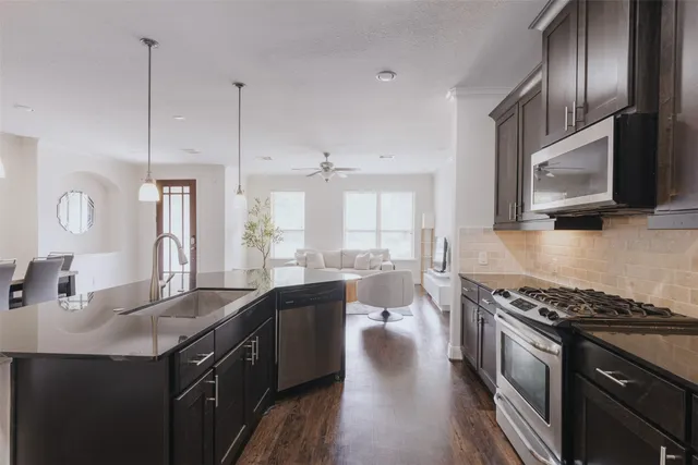 a kitchen with stainless steel appliances granite countertop a sink a stove and wooden floors