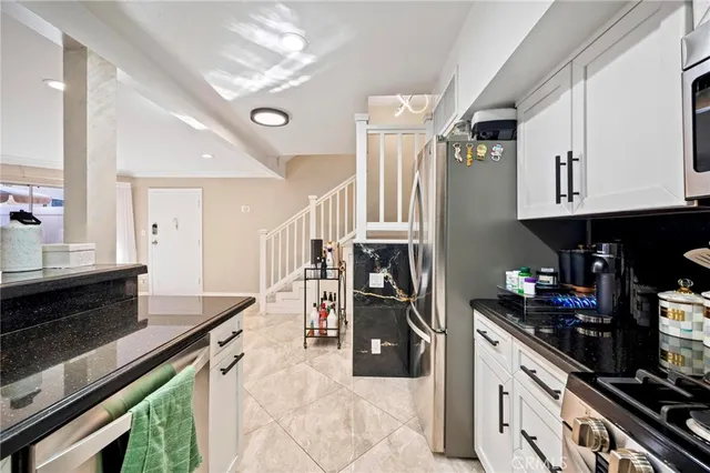 a kitchen with stainless steel appliances granite countertop a refrigerator a stove and a sink