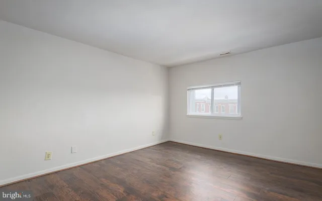 an empty room with wooden floor and window