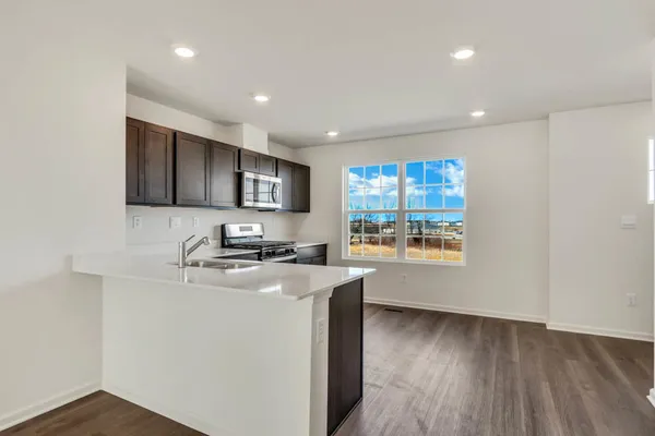 a kitchen with stainless steel appliances granite countertop a sink a stove and a refrigerator with wooden floor