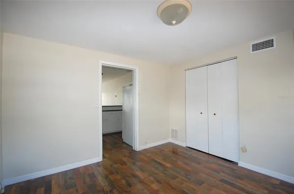 a view of an empty room with wooden floor and a closet