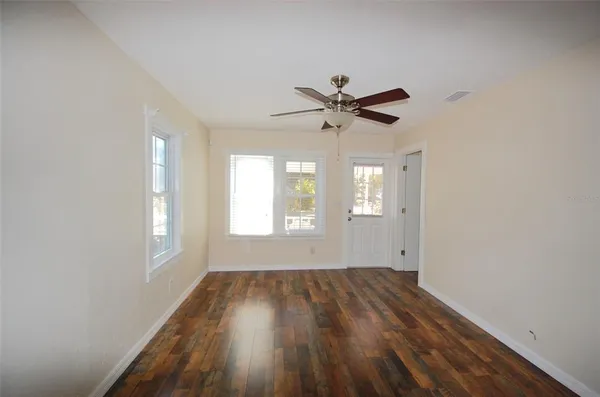 an empty room with wooden floor and windows