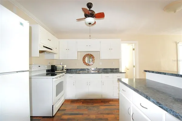 a kitchen with stainless steel appliances granite countertop a stove a sink and white cabinets