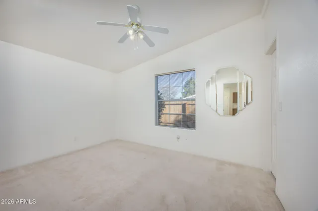 an empty room with windows and fan