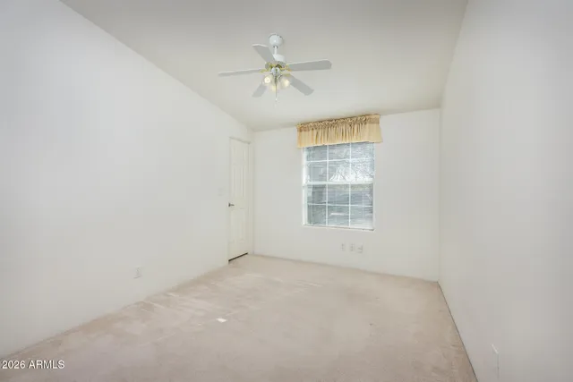 an empty room with a ceiling fan and windows