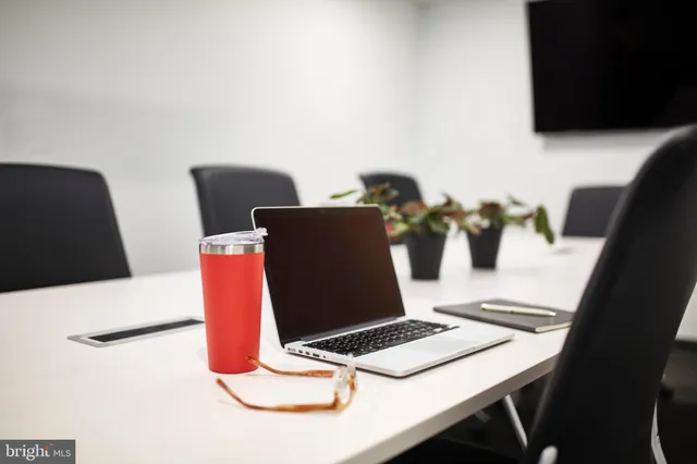 a laptop sitting on top of a table and a glass table with a view of kitchen