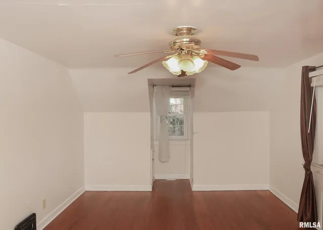 an empty room with wooden floor and chandelier fan
