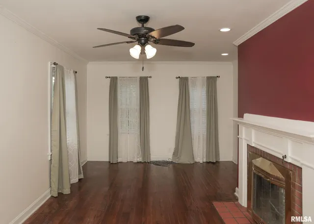 an empty room with wooden floor fireplace and windows