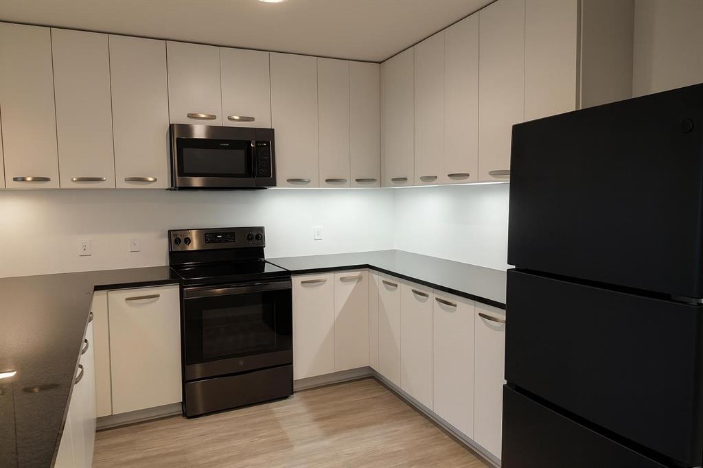 1200 Main Street, Unit 902 Dallas, TX 75202 - Photo 9 of 13 a kitchen with white cabinets and black appliances