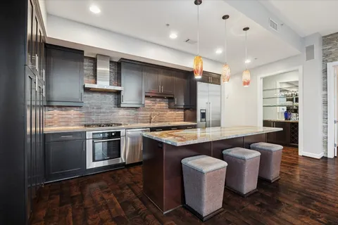 a kitchen with stainless steel appliances granite countertop a sink a stove and a wooden floors