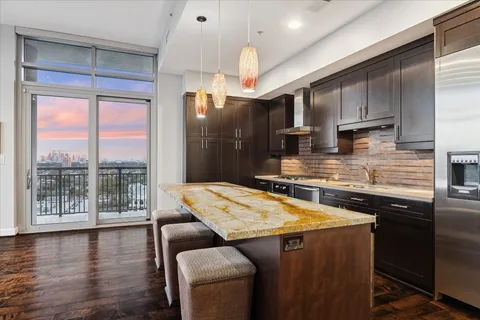 a kitchen with stainless steel appliances granite countertop a stove and a view of living room