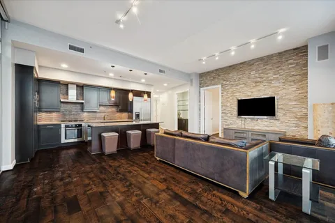 a living room with stainless steel appliances kitchen island a stove and a sink