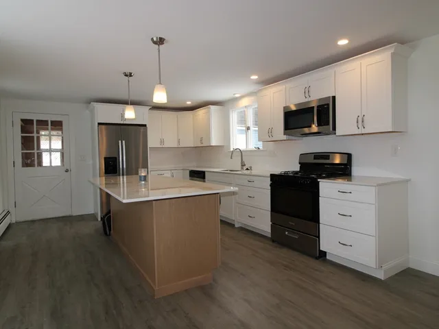 a kitchen with stainless steel appliances granite countertop a stove top oven a sink dishwasher and a microwave oven with wooden floor