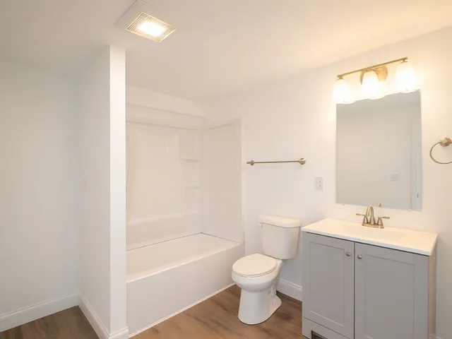 a bathroom with a bathtub shower sink vanity and toilet