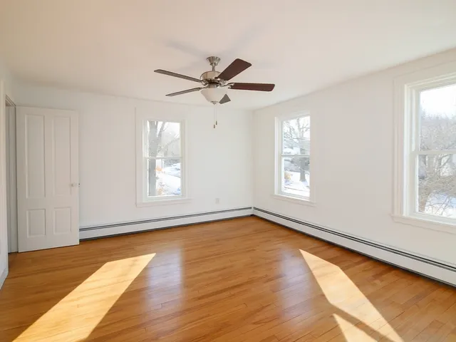 a view of an empty room with a window and wooden floor