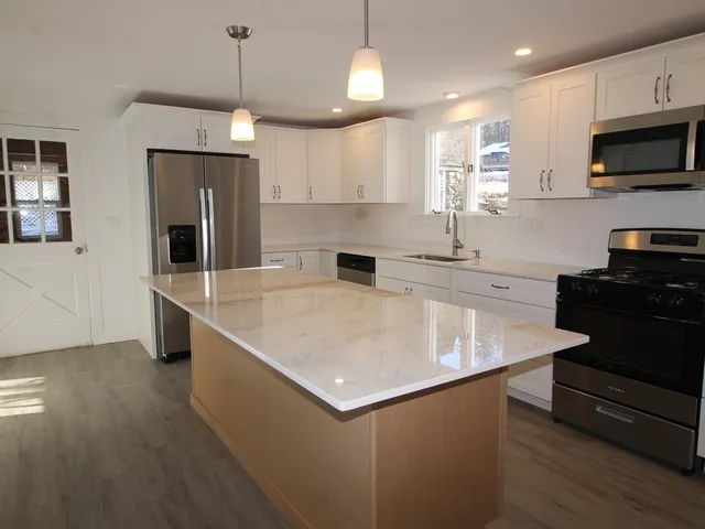 a kitchen with stainless steel appliances granite countertop a sink a stove and a refrigerator