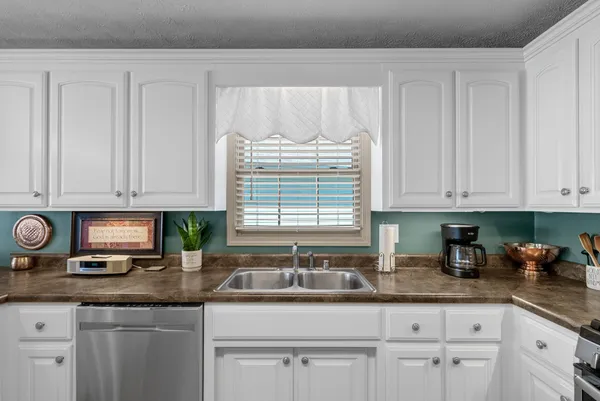 a kitchen with granite countertop white cabinets white appliances and a sink