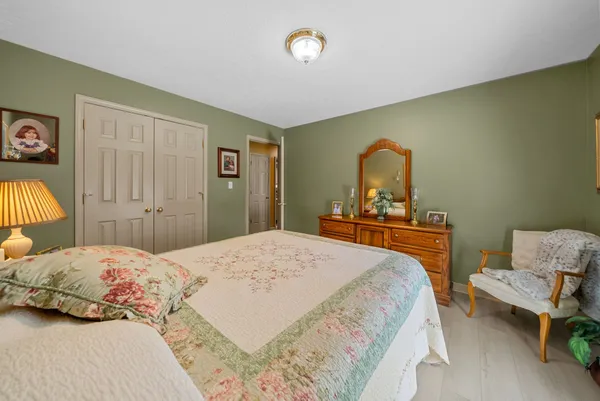 a bedroom with a bed and a dresser with mirror