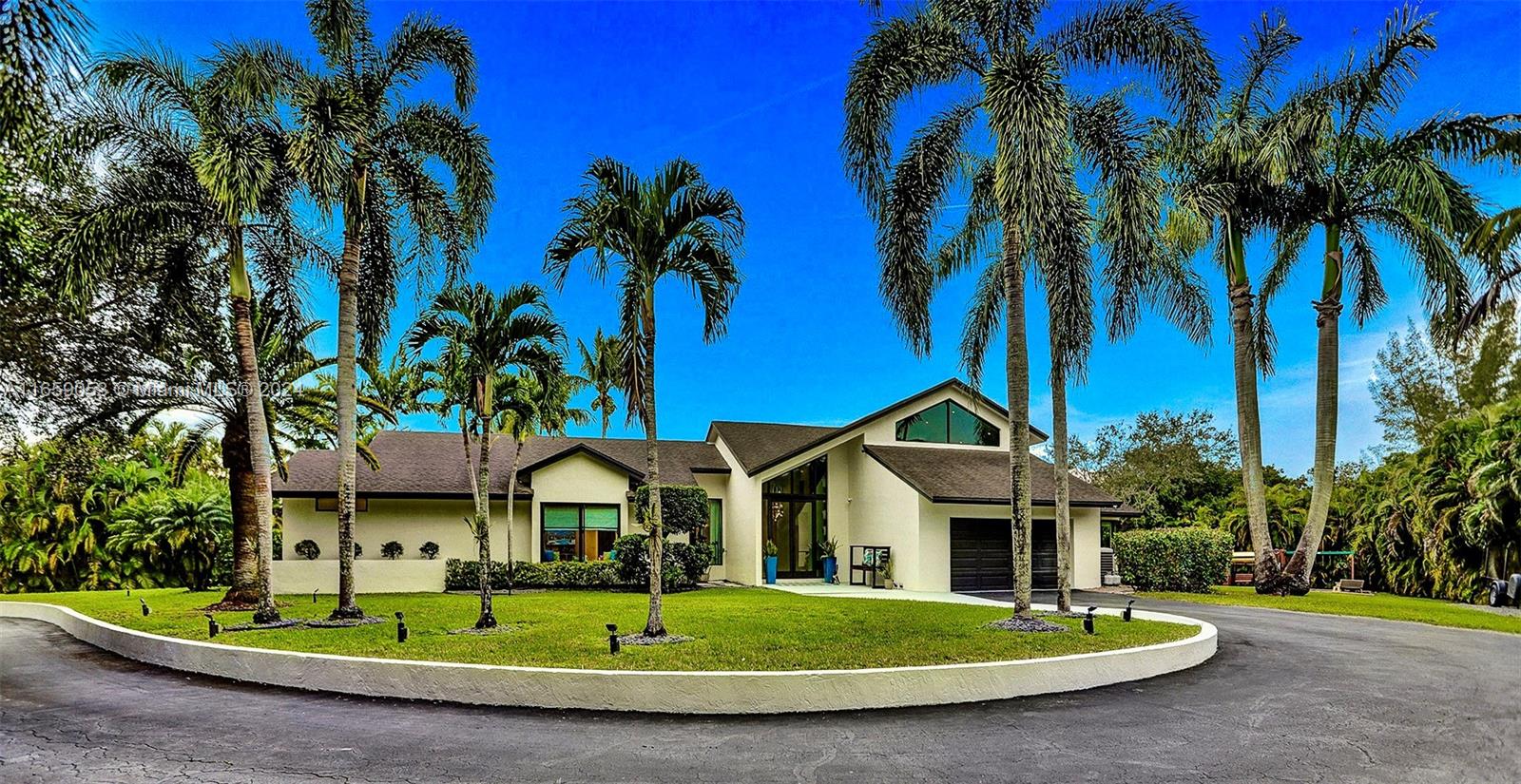 20221 Southwest 48th Place Southwest Ranches, FL 33332 - Photo 7 of 42 a front view of a house with a yard and palm trees