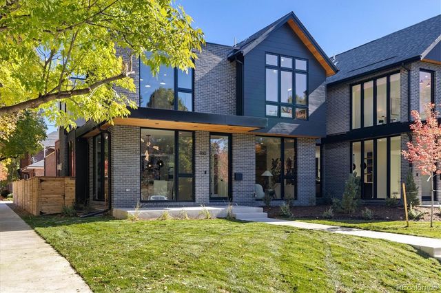 a view of a brick house with large windows and a small yard