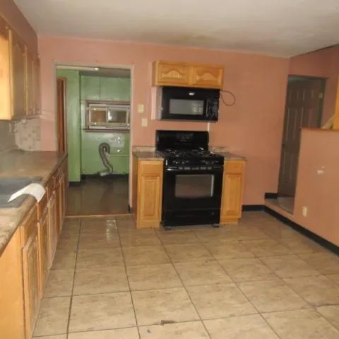 a kitchen with granite countertop a stove a sink and a microwave