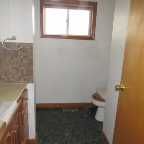 a bathroom with a granite countertop toilet and a sink