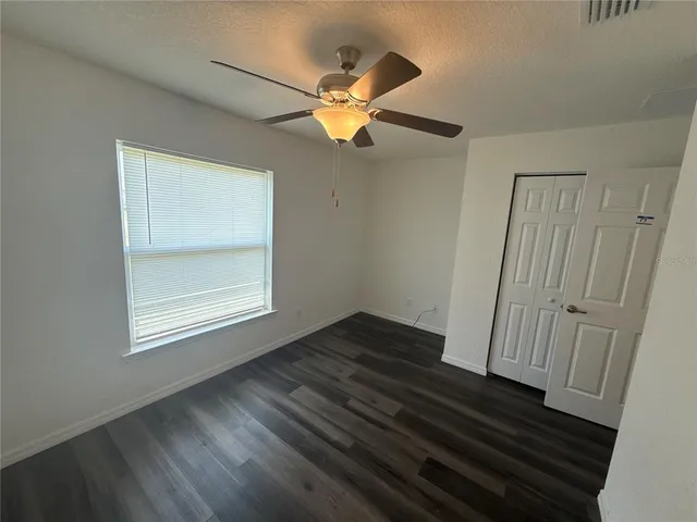 a view of empty room with wooden floor and fan