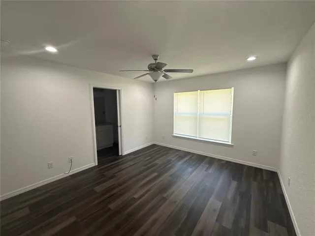 an empty room with wooden floor a ceiling fan and windows