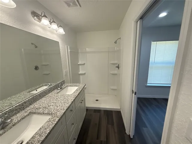 a bathroom with a granite countertop sink a mirror and a shower
