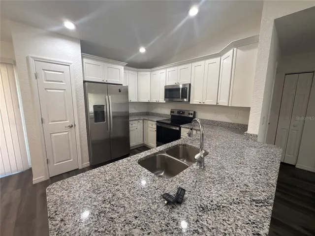 a kitchen with stainless steel appliances granite countertop a refrigerator and a sink