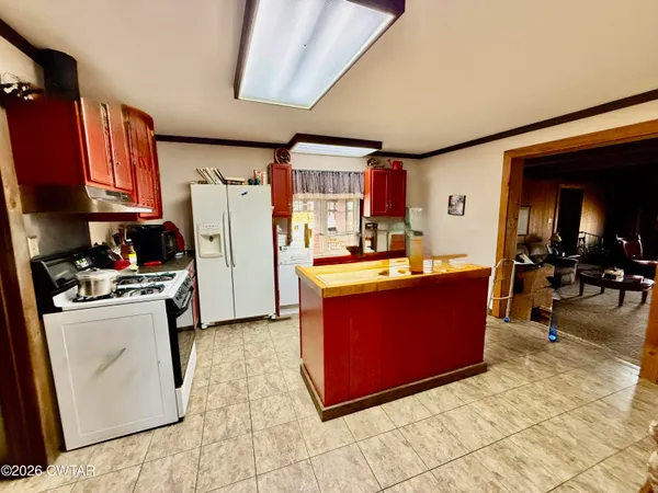a room with stainless steel appliances kitchen island granite countertop a refrigerator a stove a sink dishwasher with a dining table and chairs