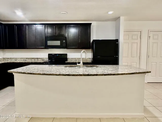 a large kitchen with granite countertop a sink and a granite counter top