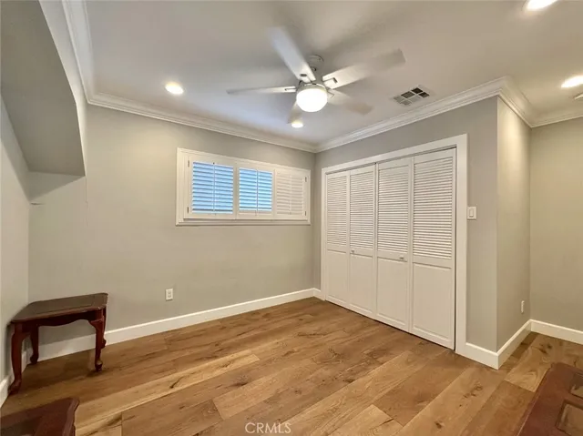 an empty room with wooden floor fan and windows