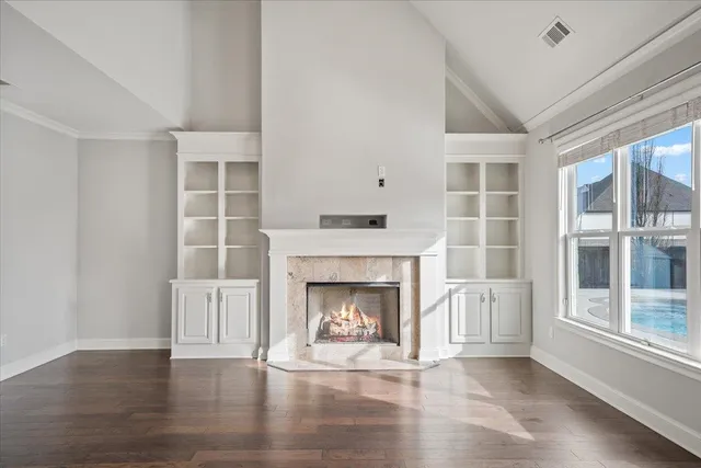 an empty room with wooden floor fireplace and windows