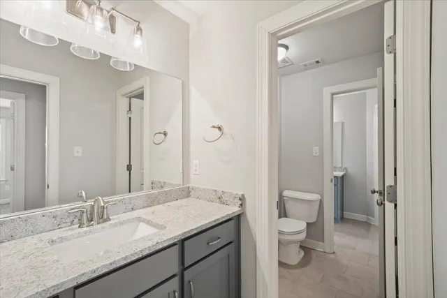 a bathroom with a granite countertop sink a toilet and a mirror