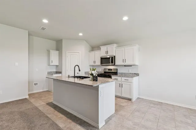 a large kitchen with stainless steel appliances kitchen island a large counter top and a refrigerator
