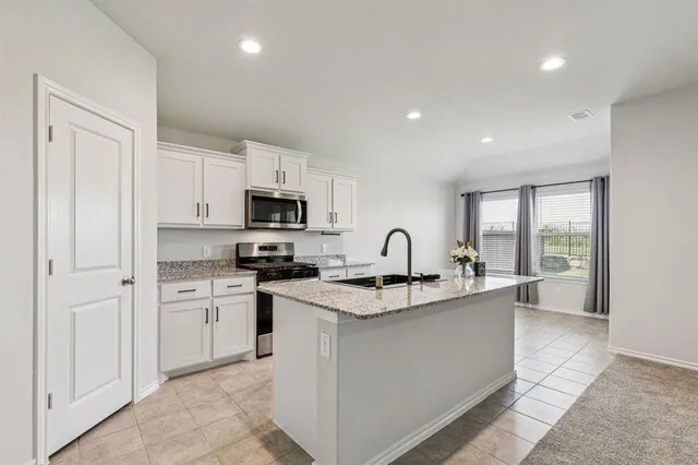 a kitchen with stainless steel appliances a sink stove and white cabinets