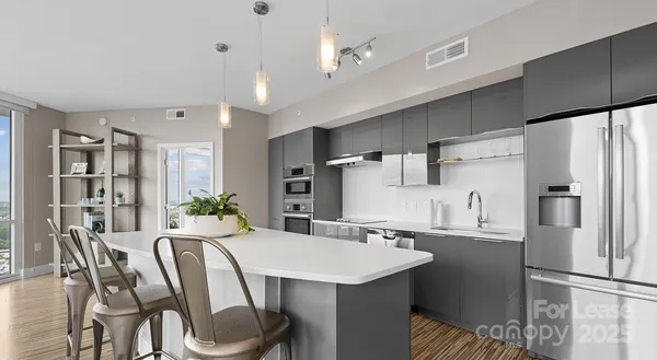 a kitchen with stainless steel appliances a dining table chairs refrigerator and sink